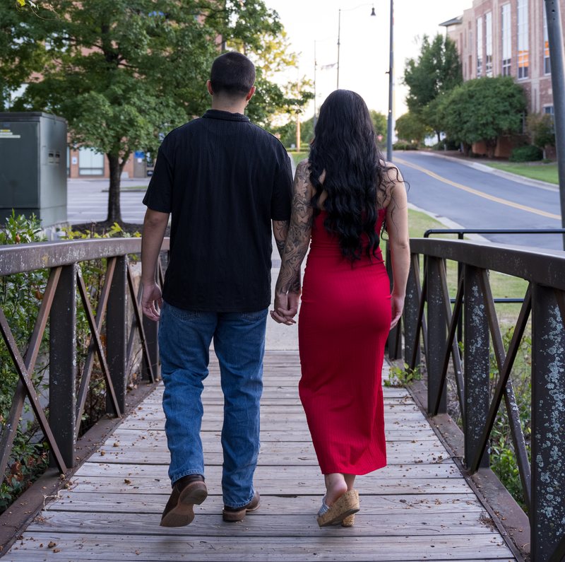 Couple walking away hand in hand across a bridge