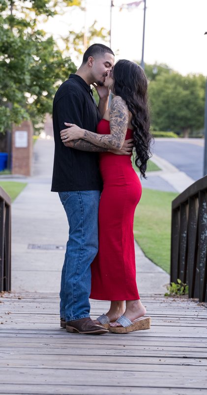 Full-length portrait of a couple kissing on a bridge