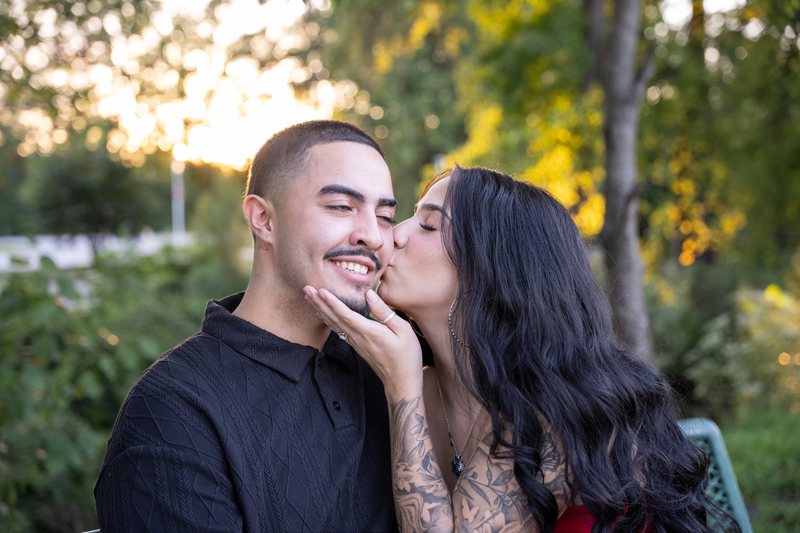 Woman kissing her smiling partner on the cheek at sunset