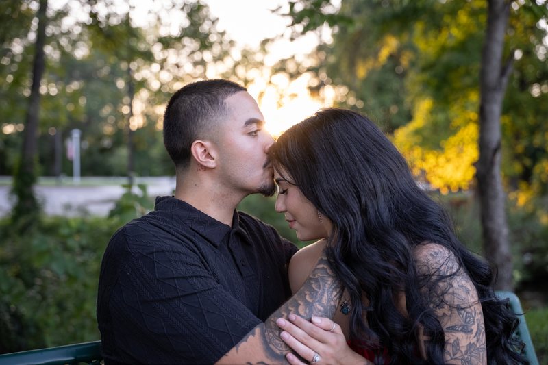 Man kissing his partner on the forehead in warm evening light