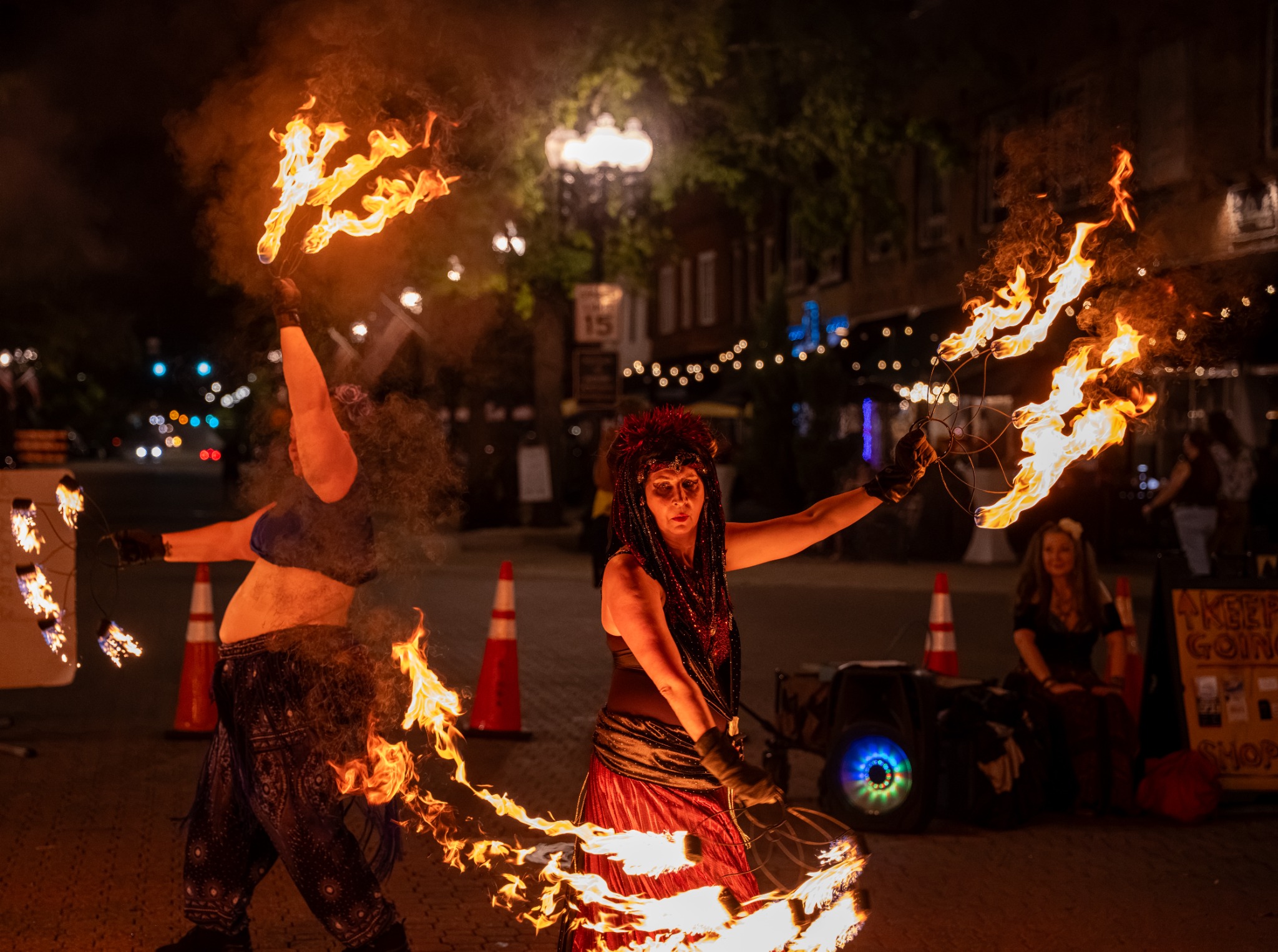 Two fire performers moving flaming fans across the nighttime street at Dogwood Nights