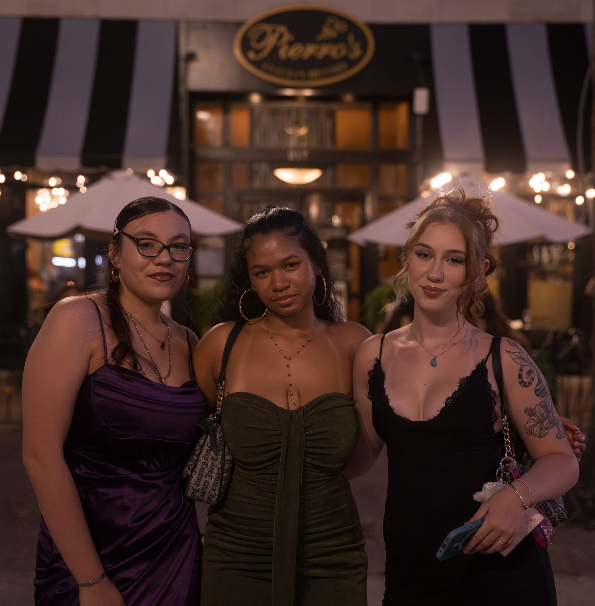 Three event guests posing together outside a restaurant at night