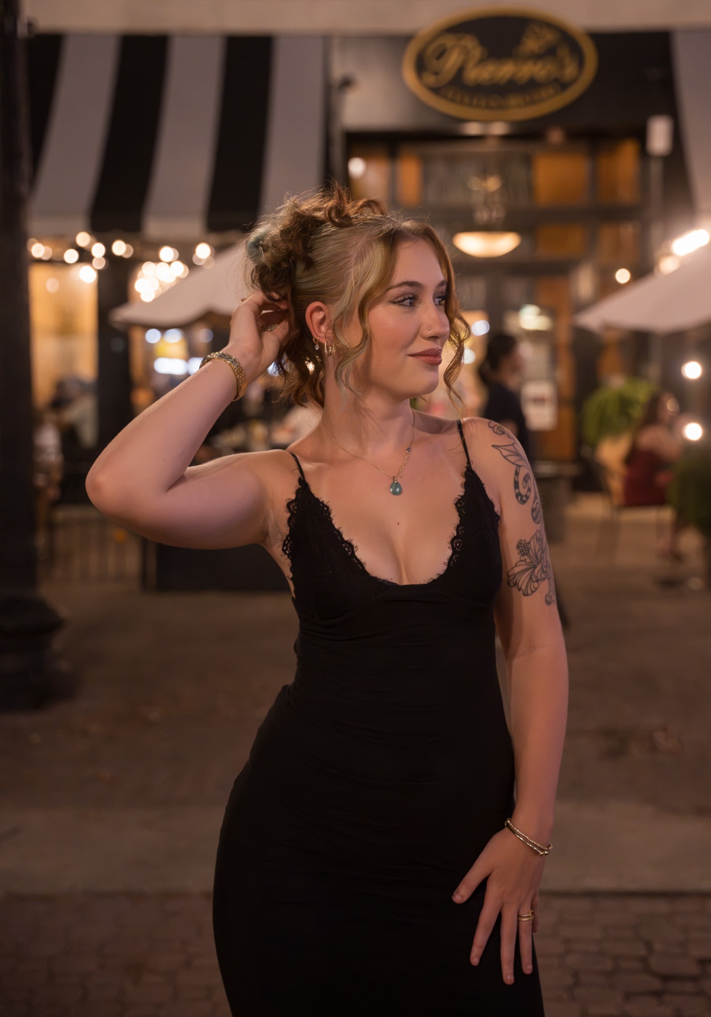Event guest in a black dress looking to the side under warm evening lights