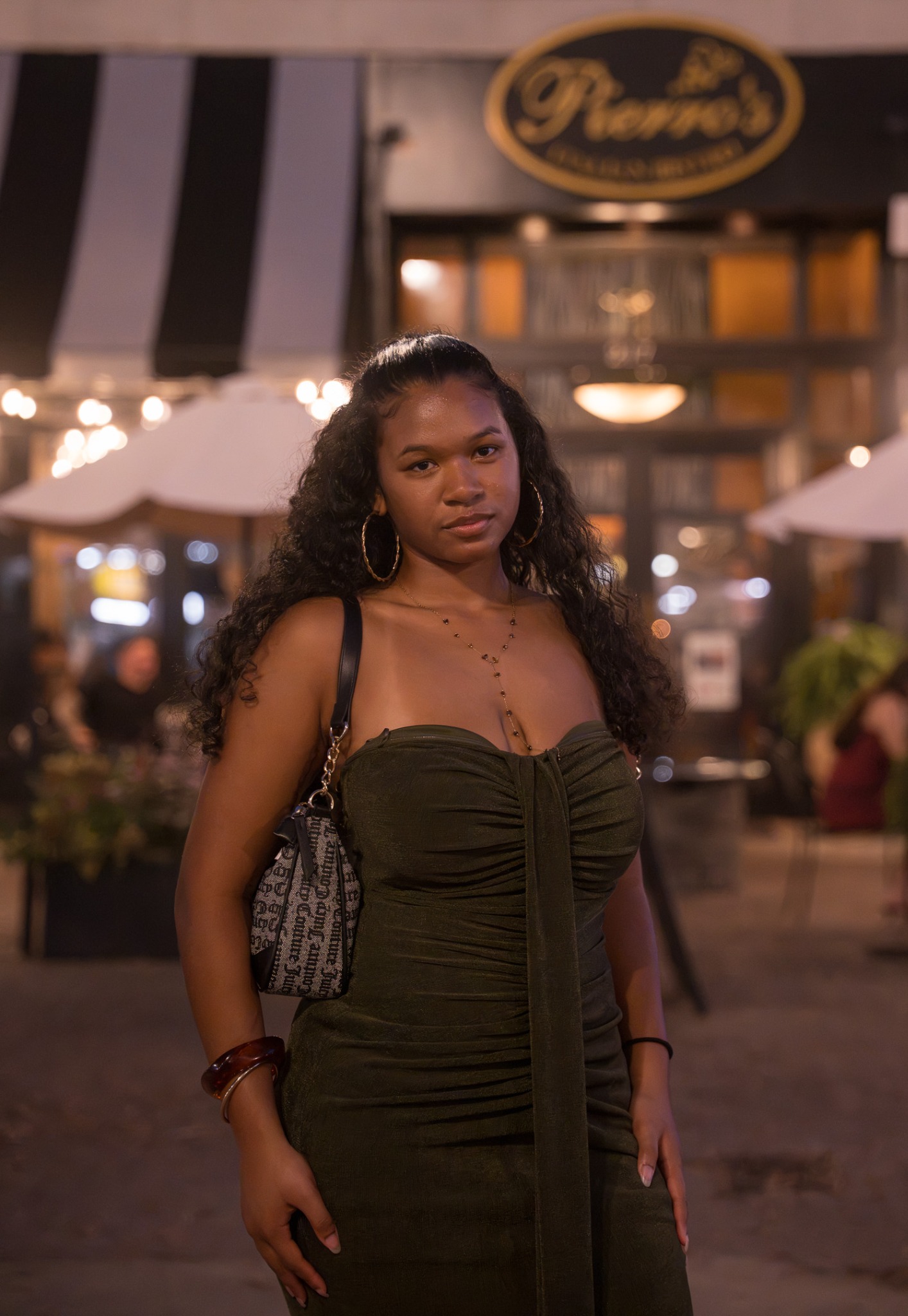 Event guest in a green dress posing outside under string lights