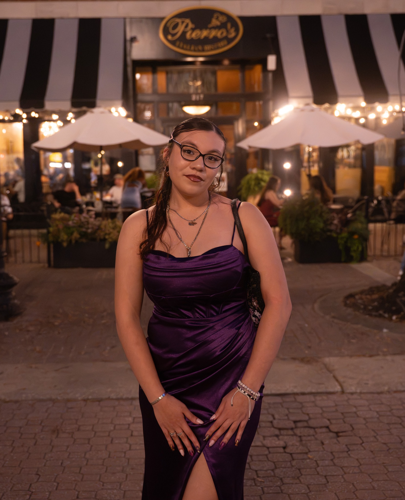 Event guest in a purple dress and glasses posing on a brick walkway