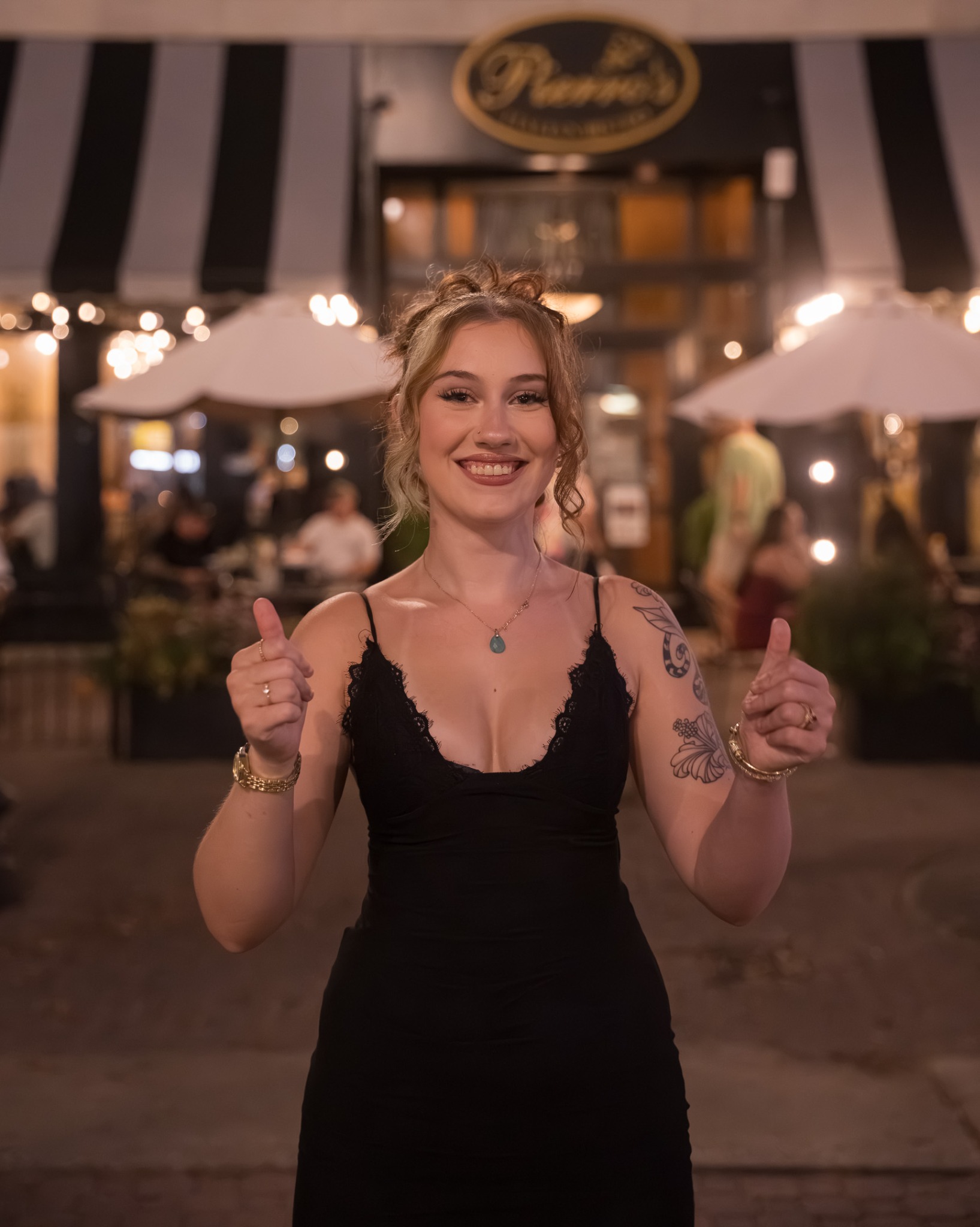 Smiling event guest in a black dress giving two thumbs up