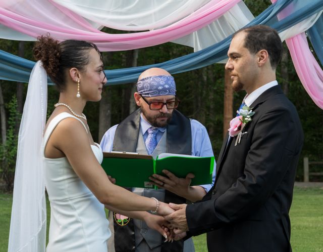 Wedding ceremony beneath pink and blue fabric
