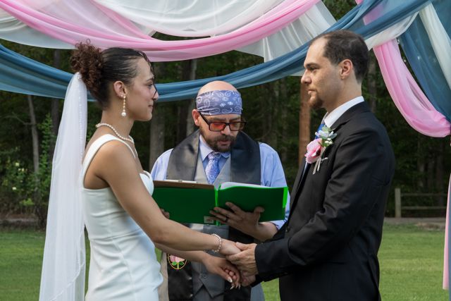Wedding ceremony beneath pink and blue fabric