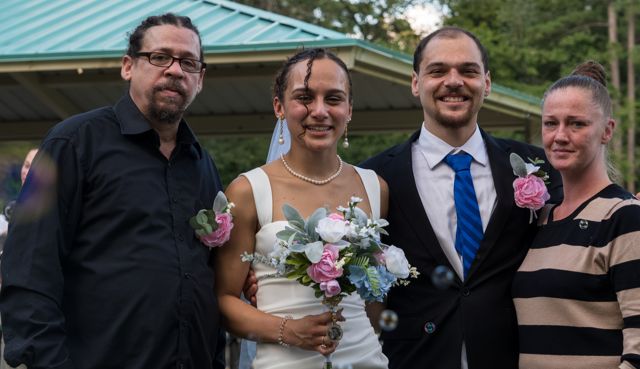 Newlyweds and guests posing together outdoors