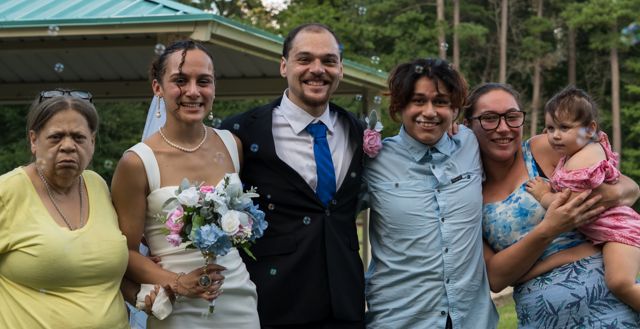 Newlyweds and guests posing together outdoors