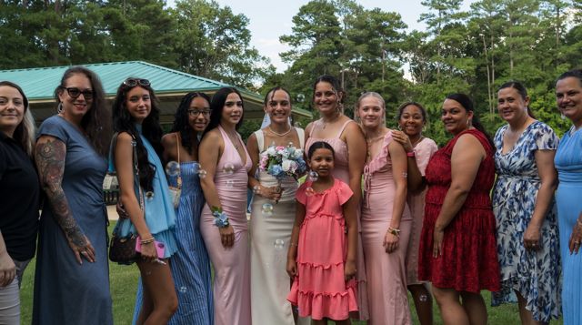 Newlyweds and guests posing together outdoors