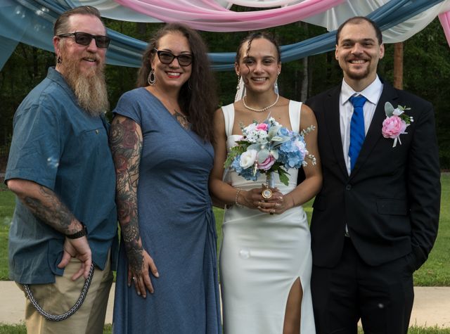 Newlyweds and guests posing together outdoors