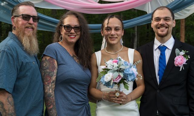 Newlyweds and guests posing together outdoors