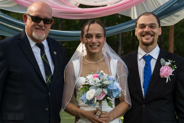 Newlyweds and guests posing together outdoors