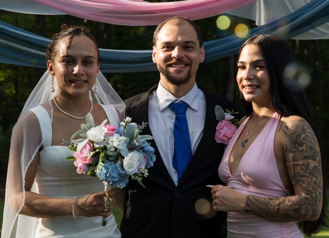 Newlyweds and guests posing together outdoors
