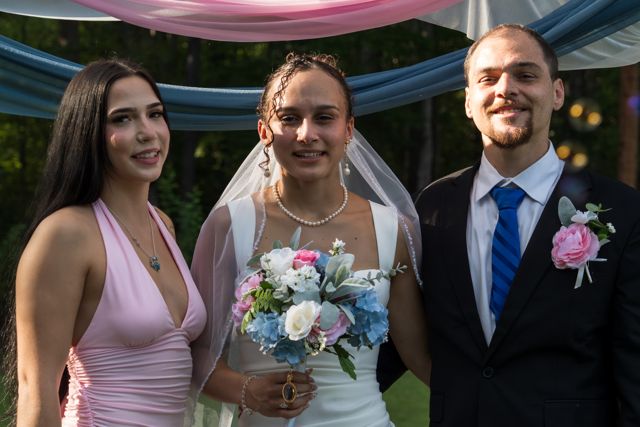 Newlyweds and guests posing together outdoors