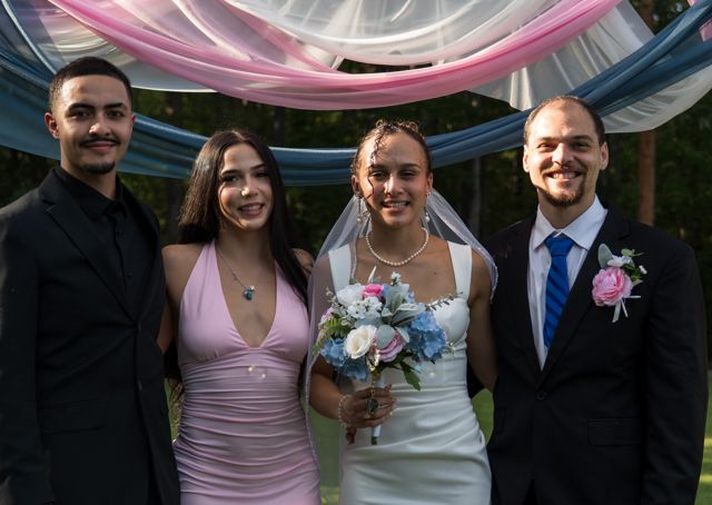 Newlyweds and guests posing together outdoors