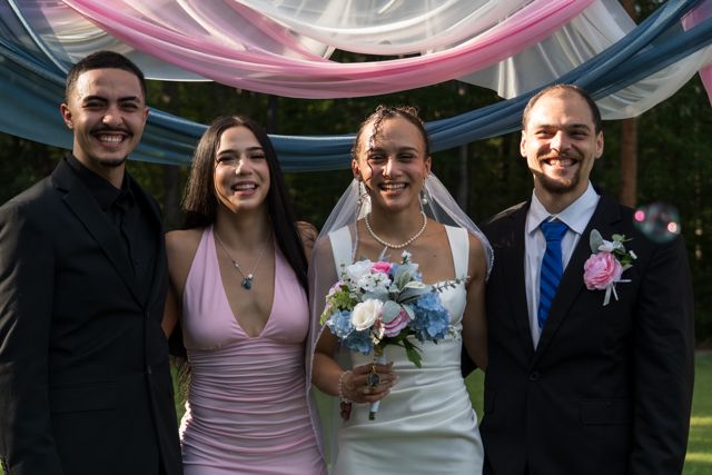 Newlyweds and guests posing together outdoors
