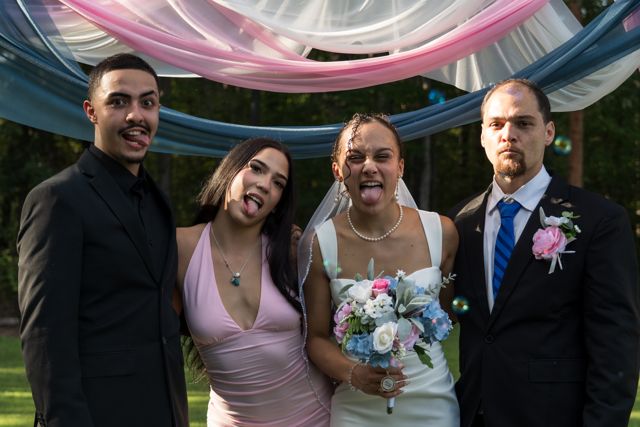 Newlyweds and guests posing together outdoors