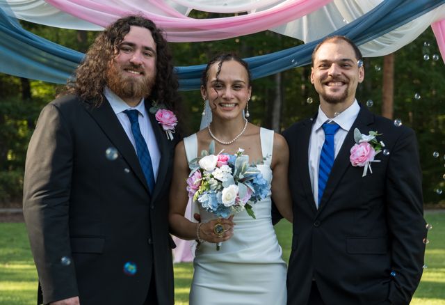 Newlyweds and guests posing together outdoors