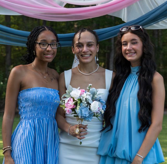 Newlyweds and guests posing together outdoors