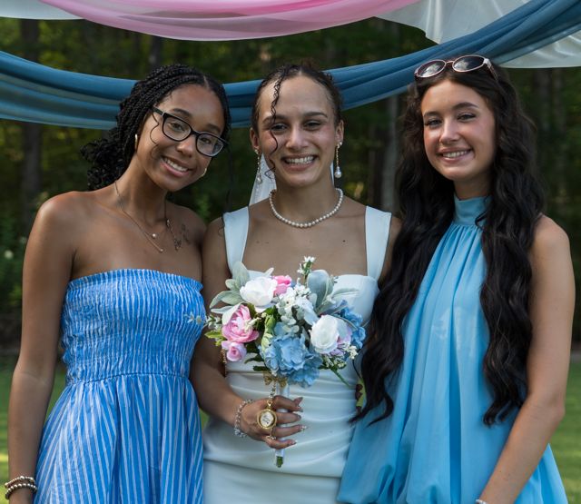 Newlyweds and guests posing together outdoors